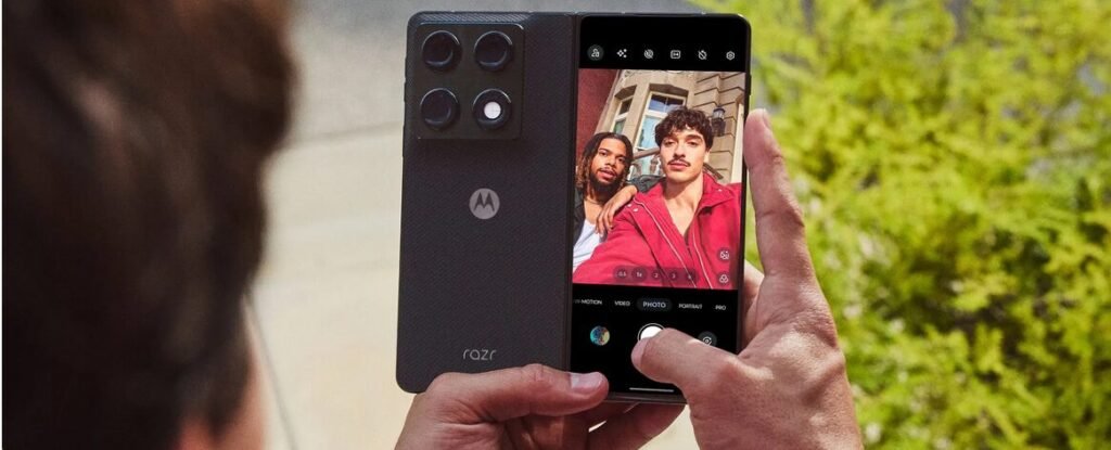 Motorola Razr Fold Launching Soon in India 13 Person using the Motorola Razr Fold camera outdoors to capture selfies with the foldable display and triple rear camera setup visible.